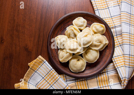 Beignets de viande maison bouilli servi dans la plaque d'argile avec sauce crémeuse. Composition dans un style rustique, sur fond de bois avec des raviolis ukrainiens. Banque D'Images