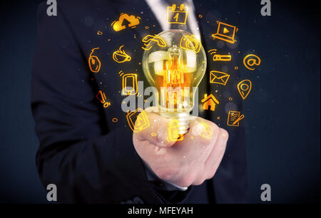 Un bureau commercial promouvoir ses idées de concept avec l'illustration des médias en ligne et les logos de l'appareil autour de l'ampoule en verre électrique. Banque D'Images