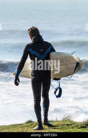 Un surfer carrying surfboard sa balade le long de la côte à Newquay dans Fistral à Cornwall. Banque D'Images