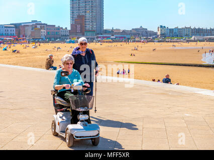 Deux femmes âgées handicapées bénéficiant d'une journée ensoleillée sur la promenade le long de la plage à Margate Banque D'Images