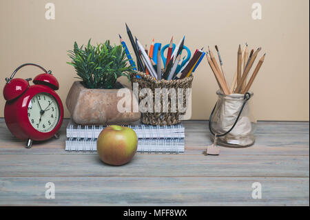 L'écriture-livres, réveil, crayons, Apple sur un fond de bois. Concept Retour à l'école Banque D'Images