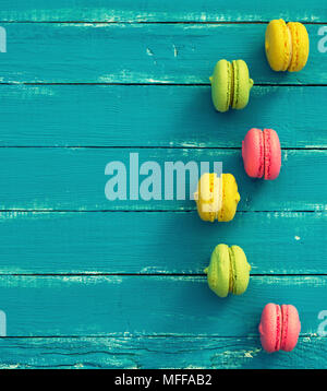 Gâteau de farine d'amande multicolores avec ses macarons à la crème sur un fond en bois bleu, copy space Banque D'Images