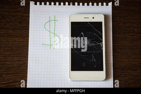 Smartphone avec un écran cassé sur une feuille de papier avec l'inscription de dollars. L'enregistrement Banque D'Images