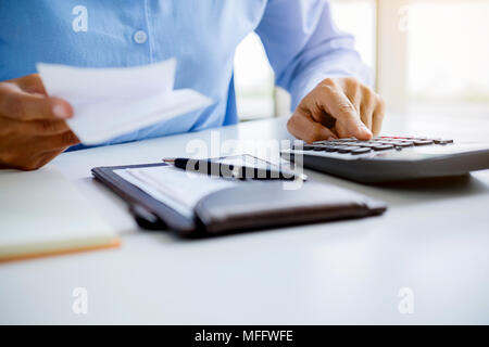 Femme avec factures et Calculatrice. Woman using calculator pour calculer les factures à la table dans le bureau. Calcul des coûts. Banque D'Images