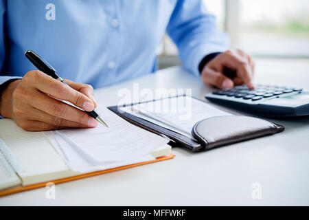 Femme avec factures et Calculatrice. Woman using calculator pour calculer les factures à la table dans le bureau. Calcul des coûts. Banque D'Images