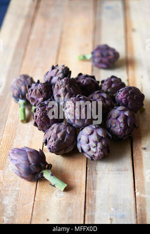 Artichauts violets frais sur une table en bois rustique. Banque D'Images