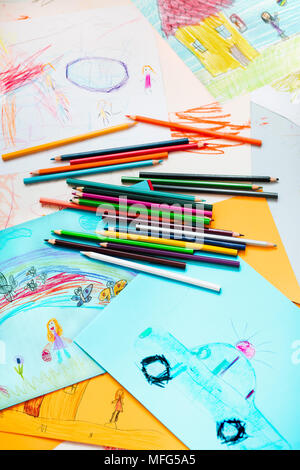 Pencil crayons éparpillés sur le bureau rempli de dessins enfantins colorés de jouer les enfants, maison, voiture. À partir de la photo ci-dessus Banque D'Images