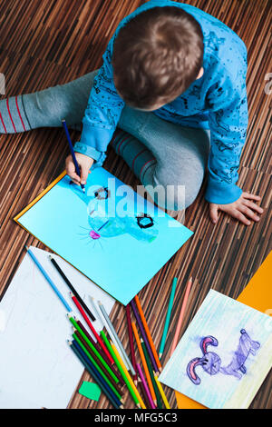 Petit garçon dessiner une image colorée d'une voiture à l'aide de crayons de couleur. En plongée des Banque D'Images