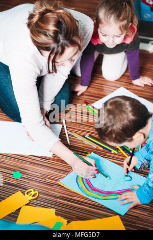 Maman aider son petit fils dimensions une image colorée de voiture à l'aide de crayons de couleur. En plongée des Banque D'Images