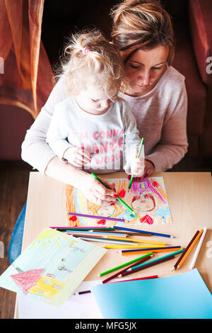 Maman avec petite fille des photos d'un dessin à l'aide de la famille de crayons à l'intérieur. En plongée des Banque D'Images