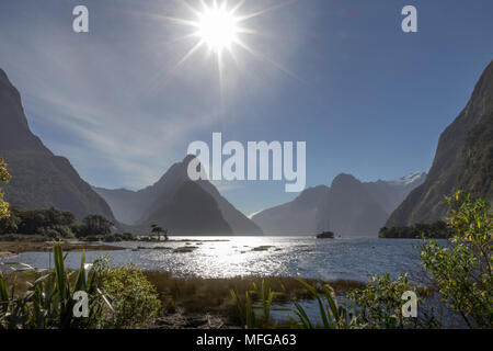 Belle étoile-effet burst que sun se rapproche d'un horizon de sommets emblématiques de l'île du sud autour de Milford Sound en Nouvelle-Zélande. Banque D'Images