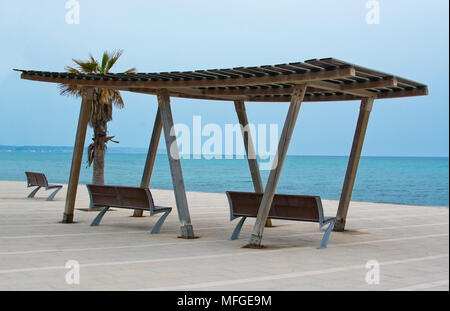 Structure d'ombrage en bois avec sièges, mer bleue de la Méditerranée sous un ciel couvert et journée horizon dans Molinar, Mallorca, Espagne. Banque D'Images