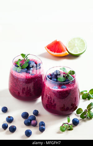 Des smoothies de bleuets et de mangue avec le jus de citron dans deux verres d'une saine alimentation. Banque D'Images