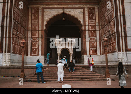 Les arcades et les fidèles à l'intérieur de la mosquée Jama Masjid sur une sombre journée à Delhi, Inde Banque D'Images