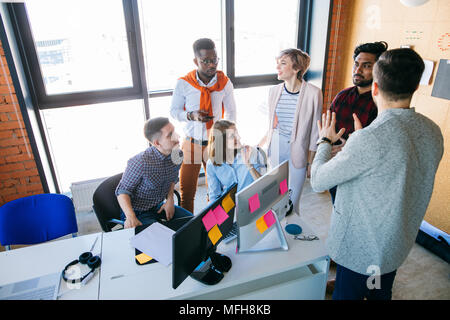 Divers ambitieux web-designers discutent de leurs plans de vue sur le lieu de travail en studio avec fenêtre panoramique. haut voir photo Banque D'Images