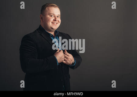 Grande taille homme d'affaires en costume noir sur fond noir Banque D'Images