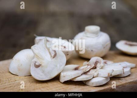 Champignons savoureux sur une table en bois. Les champignons dans la cuisine sur une planche à découper. Fond clair. Banque D'Images