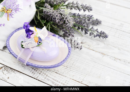 Savon lavande avec un décor en forme de papillons de nuit dans une boîte de savon avec un bouquet de lavande sur un fond de bois Banque D'Images