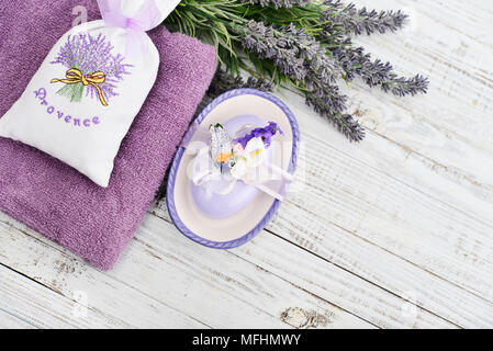 Savon lavande avec un décor en forme de papillons de nuit dans une boîte de savon avec un bouquet de lavande et de serviettes sur un fond de bois Banque D'Images