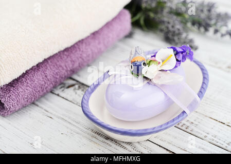 Savon lavande avec un décor en forme de papillons de nuit dans une boîte de savon avec un bouquet de lavande et de serviettes sur un fond de bois Banque D'Images