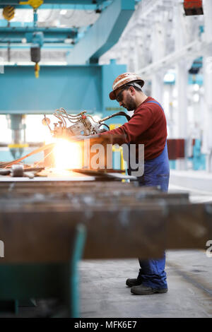 26 avril 2018, Hambourg, Allemagne : Ramazan Solmaz, opérateur de machine, fonctionne avec le '2002' de l'unité de coupe plasma autogène dans le hall de la construction navale modernisé et rénové au 2 chantier naval Blohm Voss. Un peu plus d'un an et demi après l'acquisition de Blohm Voss par le Bremer Lürssen Groupe, le chantier naval traditionnels de Hambourg est sur une nouvelle voie. Photo : Christian Charisius/dpa Banque D'Images