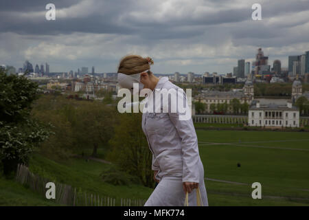 Londres, Royaume-Uni. 26 avril 2018, UK Weather : une dame dans un manteau blanc et un masque blanc s'éloigne du point de vue dans le parc de Greenwich, Londres. La vue sur Londres rapidement changé de Sun à storm cloud Crédit .Keith Larby/Alamy Live News Banque D'Images