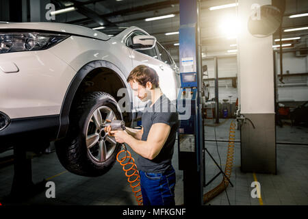 Mécanicien de voiture de retirer les écrous de roue au contrôle des freins de service dans repaur Banque D'Images