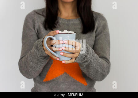 Tasse de café cacao bleu avec de la guimauve dans les mains de fille dans chandail gris, selective focus Banque D'Images