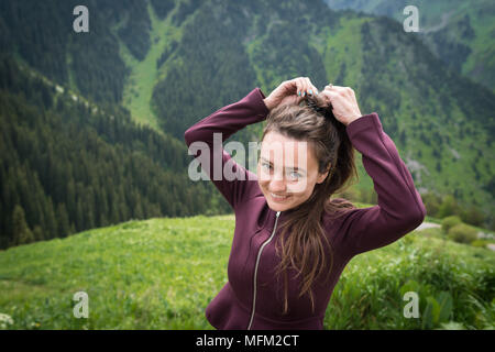 Jeune femme se tient en parc national sur fond de montagnes verdoyantes, de collines et de forêt en journée d'été. Banque D'Images