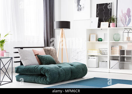 Coussins sur green futon dans une chambre moderne avec intérieur lampe en bois noir et des affiches Banque D'Images