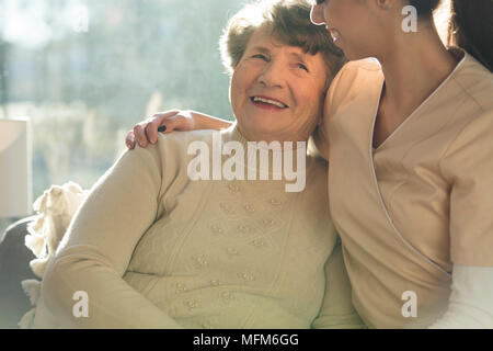 Smiling senior woman hugging soignant dans la maison de soins infirmiers Banque D'Images