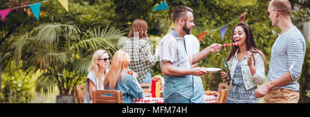 Groupe d'amis s'amuser tout en mangeant des grillades et boire de la bière pendant une fête en plein air Banque D'Images