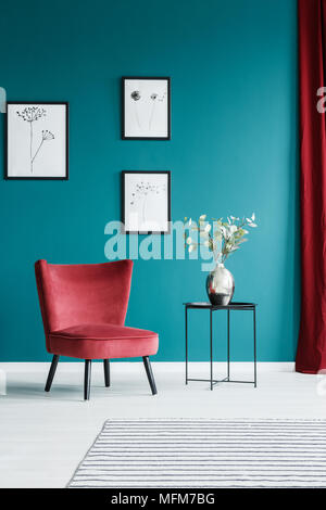 Peintures sur le mur vert dans le salon intérieur avec fauteuil rouge et le côté noir du tableau avec un vase à fleurs sur le dessus Banque D'Images