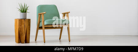 Fauteuil rétro à la menthe et des plantes sur sol en bois, une petite table à l'intérieur salon simple Banque D'Images