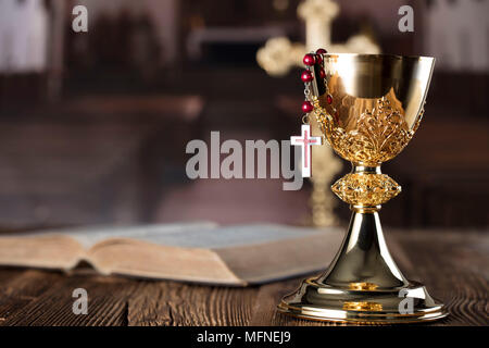 Première communion thème. La Croix, la Sainte Bible, Rosaire et Golden Chalice sur fond brun. Banque D'Images