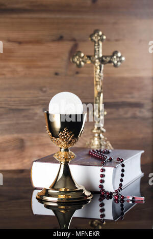 Première communion thème. La Croix, la Sainte Bible, Rosaire et Golden Chalice sur fond brun. Banque D'Images