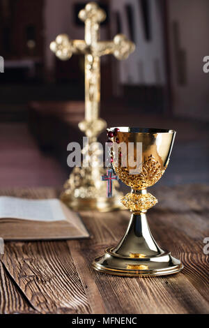 Première communion thème. La Croix, la Sainte Bible, Rosaire et Golden Chalice sur fond brun. Banque D'Images