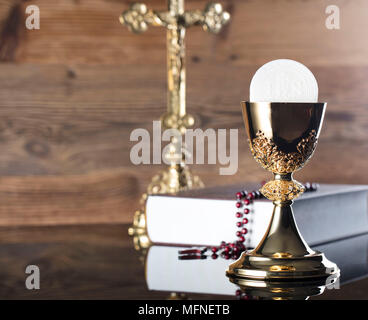 Première communion thème. La Croix, la Sainte Bible, Rosaire et Golden Chalice sur fond brun. Banque D'Images