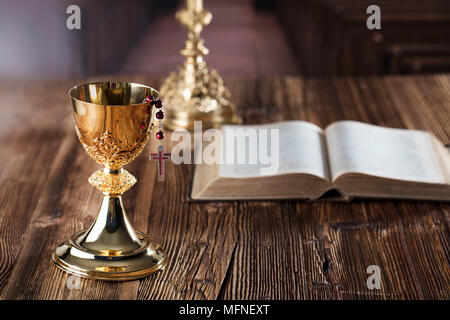 Première communion thème. La Croix, la Sainte Bible, Rosaire et Golden Chalice sur fond brun. Banque D'Images