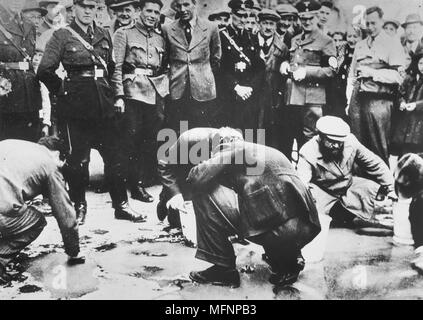 Nazis autrichiens et les habitants regardent le juifs sont forcés d'obtenir sur ses mains et genoux et frottez le pavé, 1938. Banque D'Images