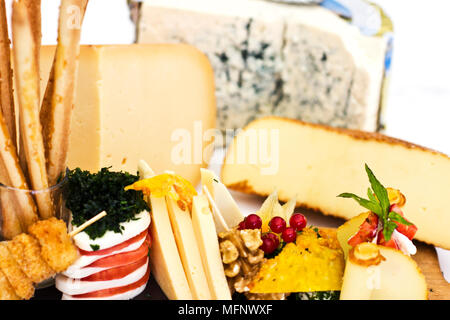Plateau de fromages : le roquefort avec moisissure bleue, cheddar, fromage fumé, mozzarella sur une planche de bois. Décorées avec la groseille, la fraise et petits fruits Banque D'Images