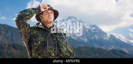 Jeune soldat en uniforme militaire sur les montagnes Banque D'Images