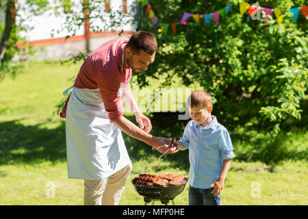 Père et fils la cuisson des viandes sur le gril du barbecue Banque D'Images