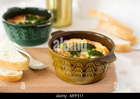 Oeufs brouillés cuits au four avec du brocoli, des saucisses et fromage servi avec des tranches de pain. De style rustique, selective focus. Banque D'Images