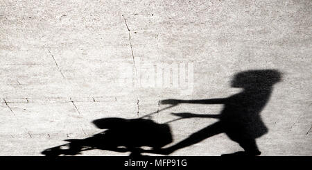 Ombre silhouette d'une jeune femme en poussant une poussette sur les trottoirs de la ville en noir et blanc Banque D'Images