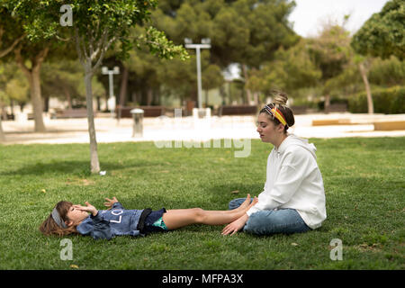 Deux soeurs jouant dans un parc assis sur l'herbe. Pris dans un parc dans la ville de San Vicente del Raspeig dans la province d'Alicante en Espagne. Banque D'Images