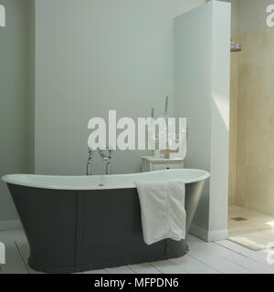 Une salle de bains avec une baignoire de style traditionnel, salle de douche, des porte-bougie sur une commode, murs blancs et parquet en bois blanc Banque D'Images