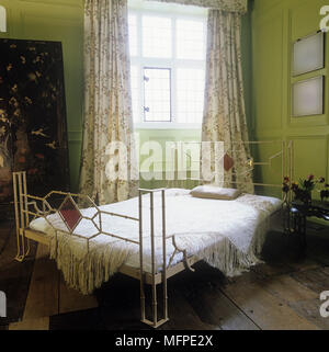 Vert chambre avec des murs lambrissés et des pans de fer forgé lit avec deux pas. Banque D'Images