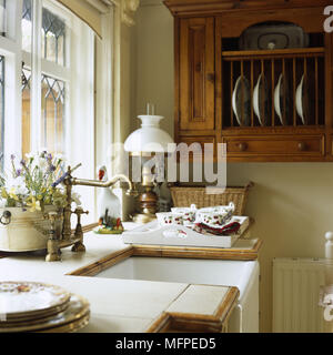 Détail d'un style victorien traditionnel avec un grand évier de cuisine robinet laiton en face d'une armoire en bois avec des plaques. Banque D'Images