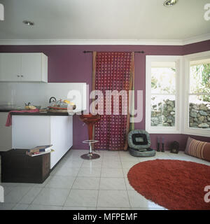 View of modern cuisine américaine avec coin repas doté d''une selle rouge et un grand tapis de laine rouge Banque D'Images